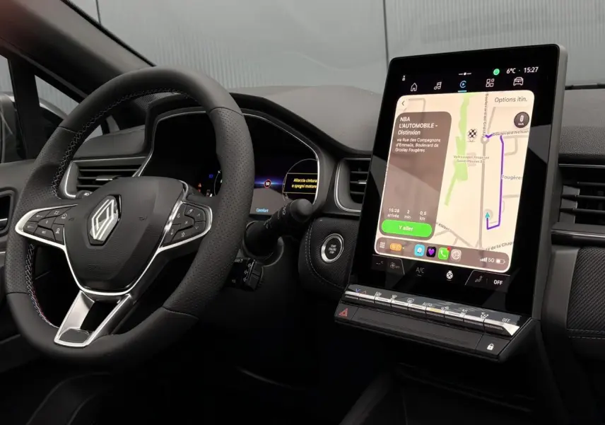 Vue intérieure du tableau de bord du Renault Captur 2025, volant avec logo et écran tactile vertical affichant la navigation.