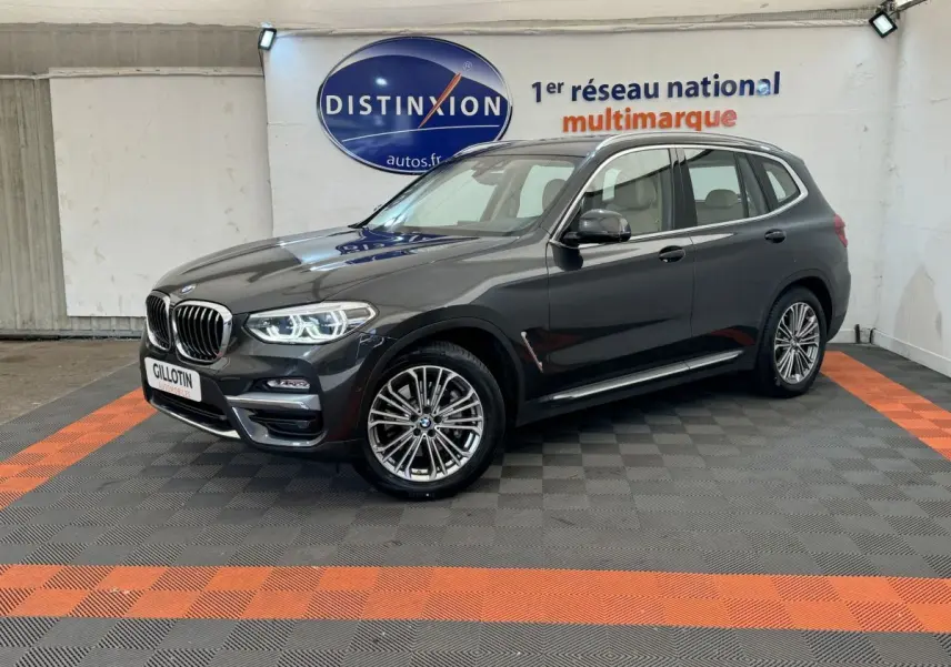 BMW X3 xDrive30d gris foncé vue 3/4 avant droit, avec phares LED allumés dans un showroom.