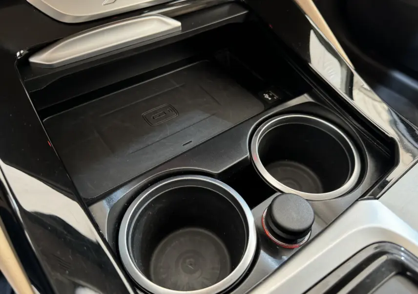 Gros plan sur la console centrale noire du BMW X3 xDrive30d 2018 avec porte-gobelets et zone de recharge sans fil.