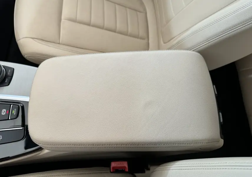 Gros plan sur l'accoudoir central beige et la console centrale d'une BMW X3 Luxury 2018, intérieur cuir clair.