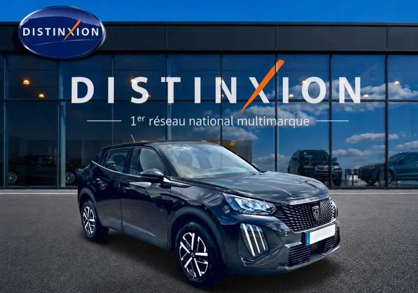 Peugeot 2008 noir en 3/4 avant droit, avec calandre distinctive et feux LED verticaux, devant showroom Distinxion.