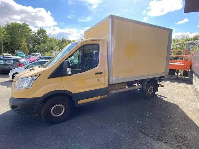 Ford Transit Chassis Cabine jaune vu de profil côté gauche, avec caisse fermée et hayon arrière visible.