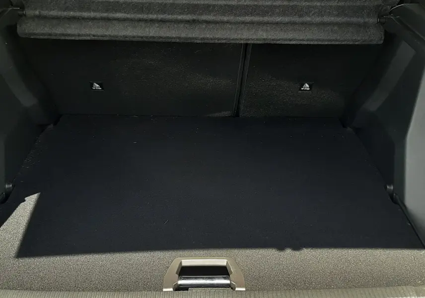 Coffre ouvert du Peugeot 2008 gris Artense, vue intérieure montrant l'espace de chargement vide et la moquette noire.