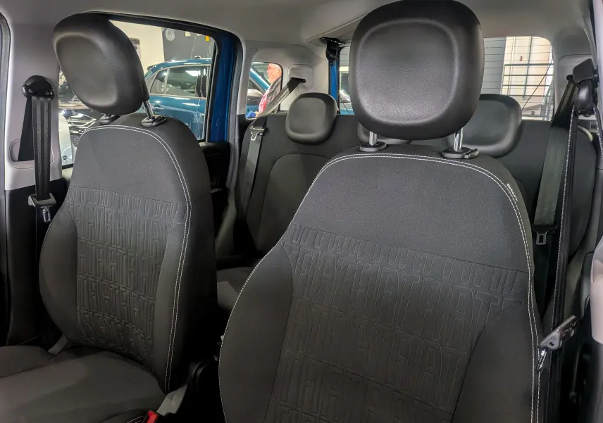 Vue intérieure des sièges avant et arrière en tissu noir avec motifs FIAT sur une Fiat Panda Bleu Italia 2025.