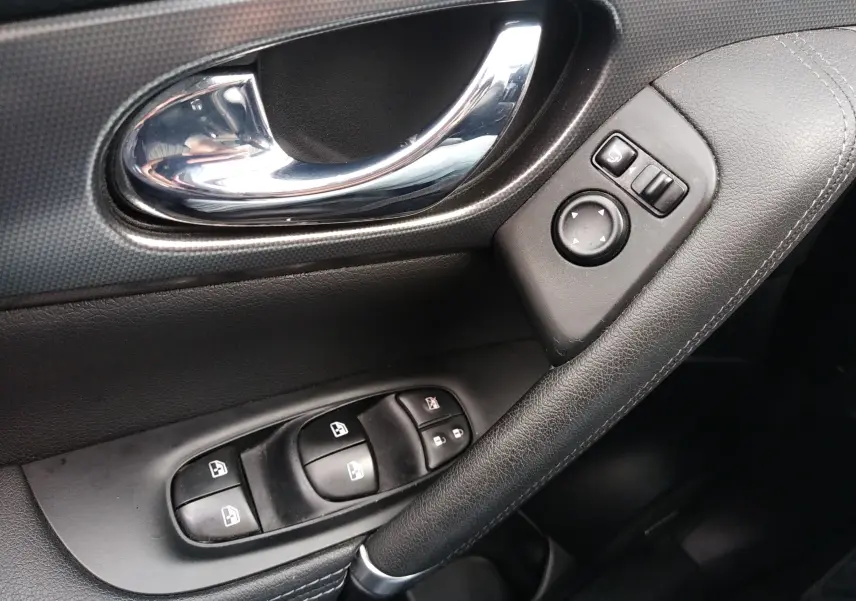 Poignée de porte intérieure côté gauche en cuir noir avec commandes des vitres et réglage des rétroviseurs du Nissan Qashqai Tekna 2019.