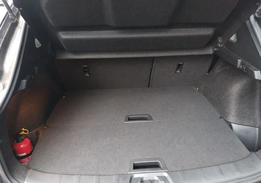 Vue intérieure du coffre du Nissan Qashqai 1.2 DIG-T 115ch Tekna noir 2019, avec plancher plat et extincteur rouge visible à gauche.