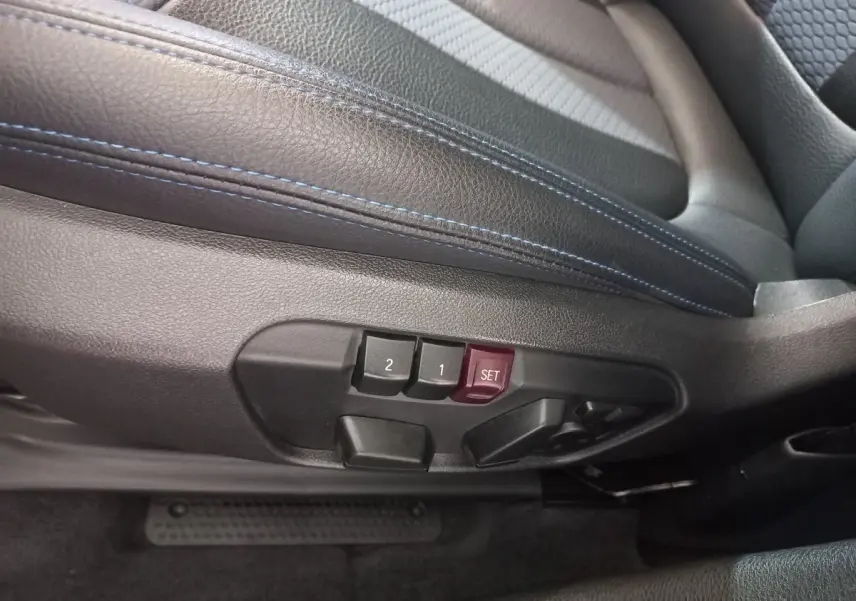 Gros plan sur les commandes de réglage mémoire des sièges en cuir noir avec surpiqûres bleues du BMW X1 xDrive20d M Sport 2022.
