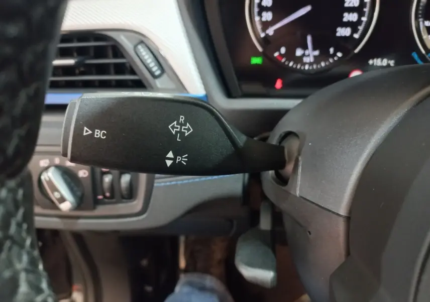 Gros plan sur la manette de clignotant à gauche du volant dans l’habitacle noir d’un BMW X1 xDrive20d 2022.