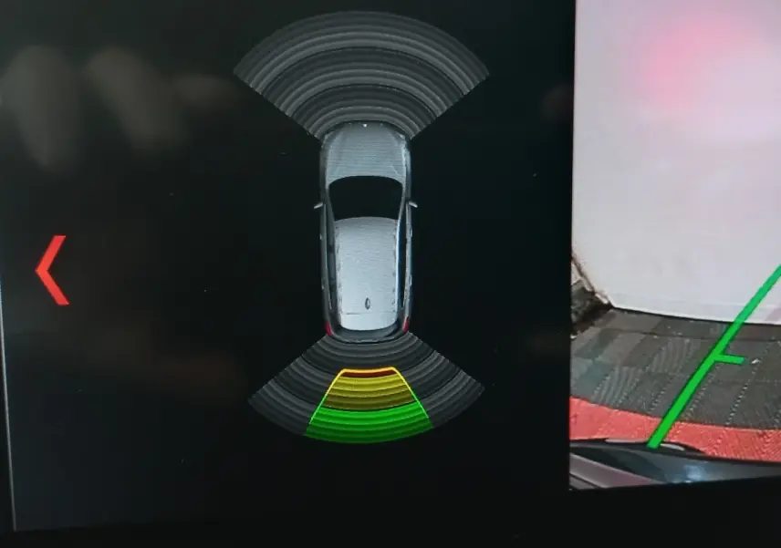 Vue de dessus sur l'écran de stationnement montrant un BMW X1 noir avec aides au stationnement activées.