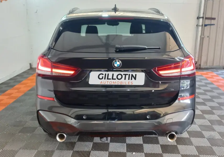 Vue arrière d'un BMW X1 xDrive20d noir 2022 avec feux LED allumés et double sortie d'échappement visible.