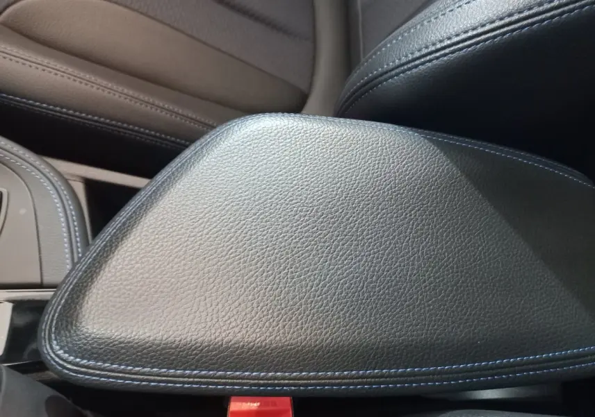 Détail de l'accoudoir central en cuir noir avec surpiqûres bleues dans l'habitacle du BMW X1 xDrive20d M Sport 2022.