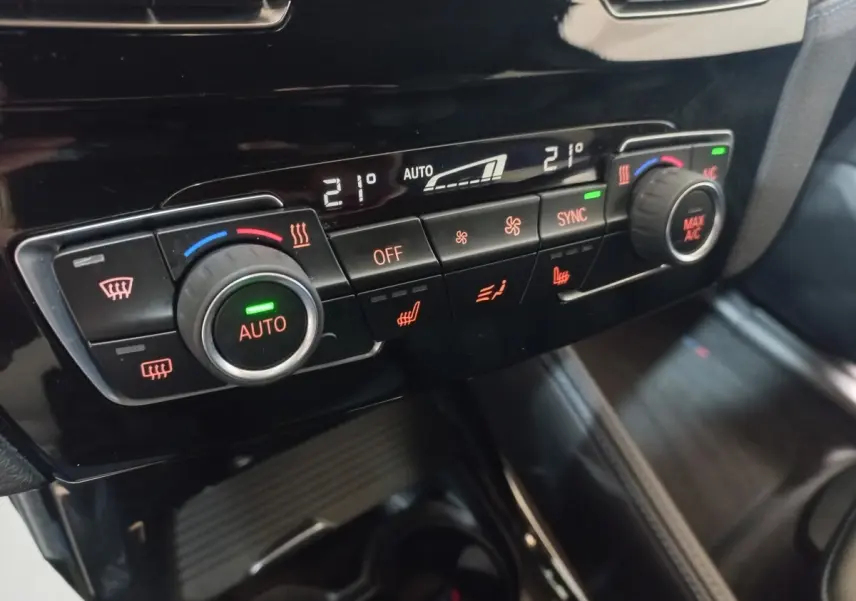 Détail de la console centrale noire du BMW X1 2022, montrant les commandes de climatisation automatique bi-zone.