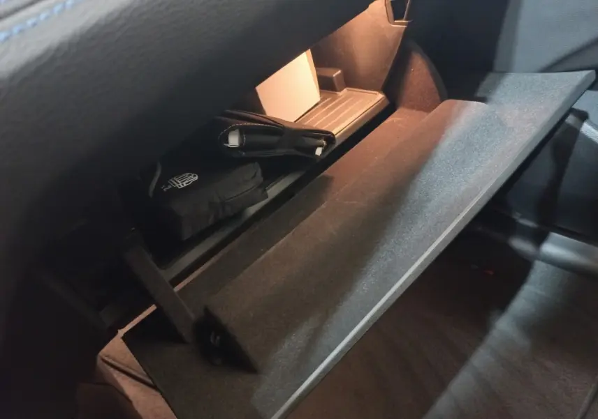 Intérieur BMW X1 xDrive20d 2022, vue sur la boîte à gants ouverte avec éclairage intérieur et objets rangés.