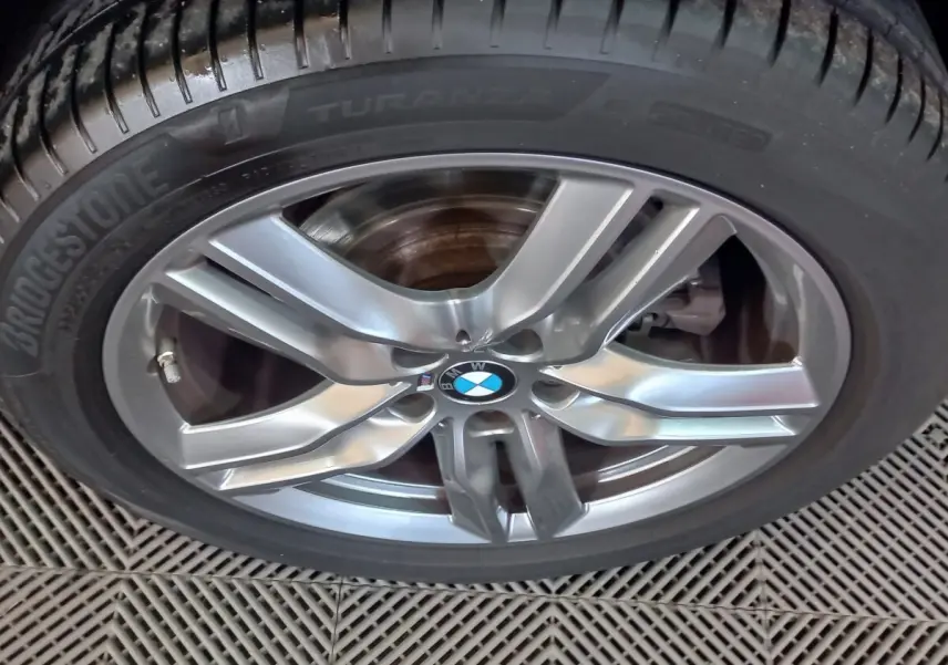 Gros plan sur la jante alliage grise et le pneu Bridgestone d’un BMW X1 xDrive20d noir, version M Sport 2022.