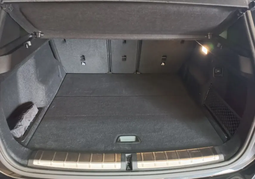 Coffre ouvert vu de face d'un BMW X1 noir 2022, avec tapis noir et éclairage latéral intérieur allumé.