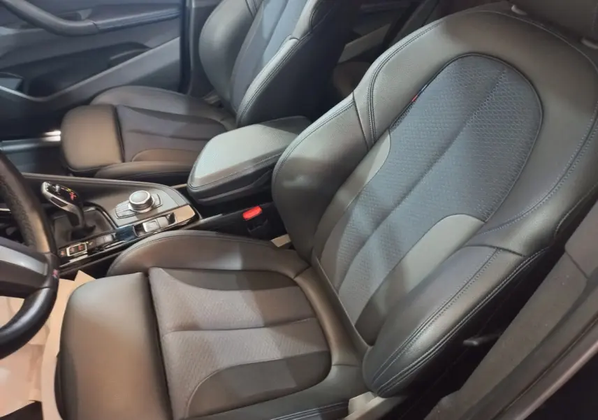 Vue rapprochée des sièges avant en cuir noir et console centrale du BMW X1 xDrive20d M Sport 2022.