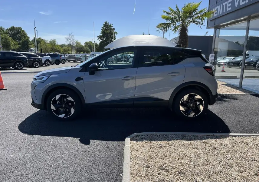 Renault Captur 2025 gris Rafale toit noir en profil droit, avec jantes noires et détails modernes visibles.
