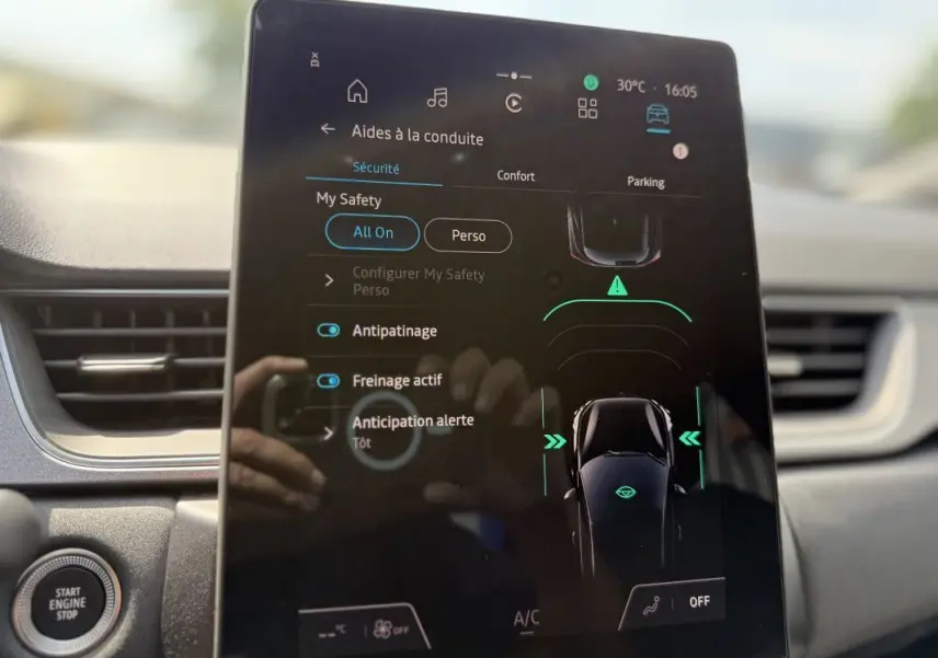 Écran tactile central du Renault Captur 2025 affichant les aides à la conduite, avec tableau de bord gris en arrière-plan.