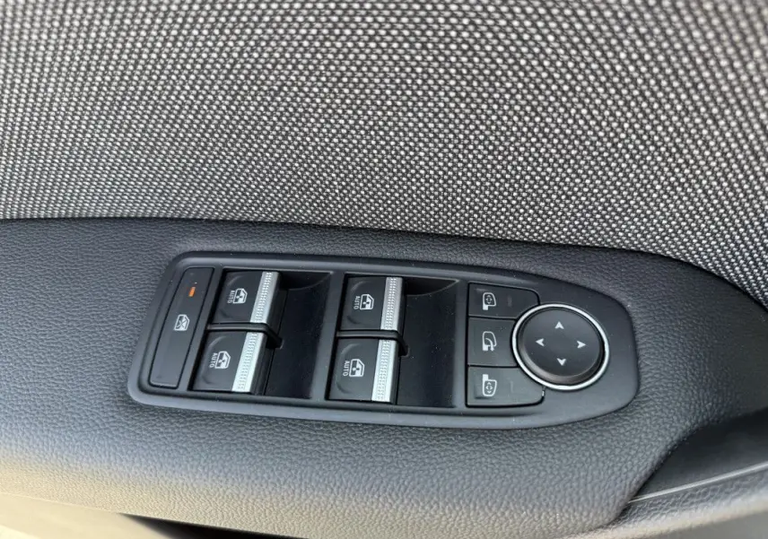 Gros plan sur les commandes de lève-vitres et rétroviseurs côté conducteur d’un Renault Captur gris Rafale 2025.