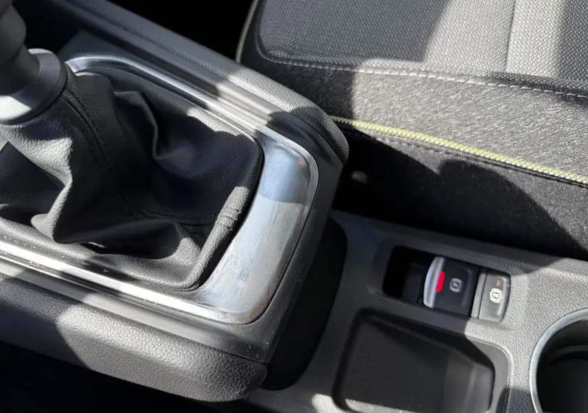 Gros plan sur le levier de vitesses manuel et le frein à main électronique du Renault Captur gris Rafale, intérieur tissu noir.