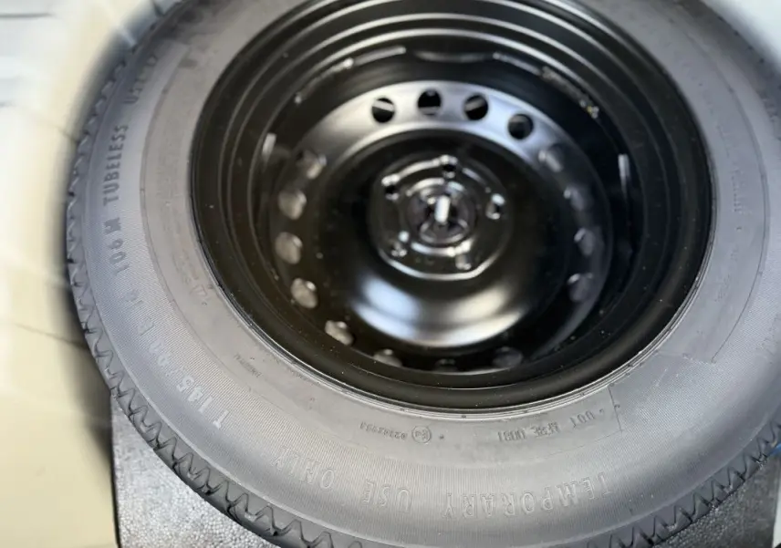 Gros plan sur la roue de secours noire du coffre du Renault Captur gris Rafale toit noir 2025.