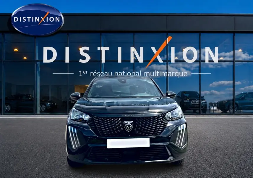 Vue frontale d'un Peugeot 2008 noir 2025 avec calandre distinctive et feux LED verticaux, devant un showroom Distinxion.