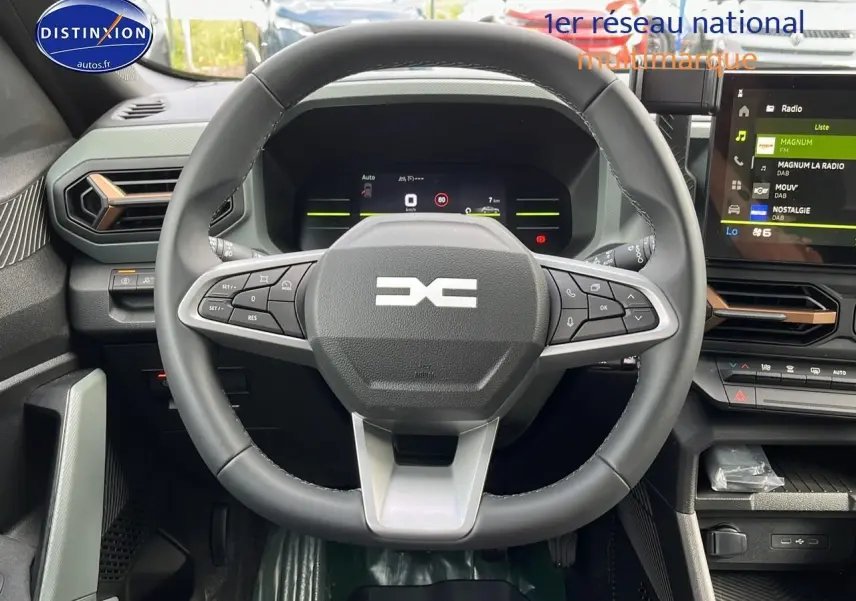 Vue centrée sur le volant multifonction et tableau de bord numérique du Dacia Duster 2025 couleur Sandstone.