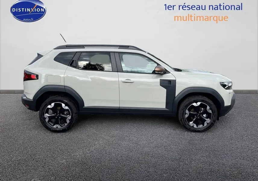 Profil droit du Dacia Duster 2025 Sandstone avec barres de toit et jantes noires semi-diamantées.