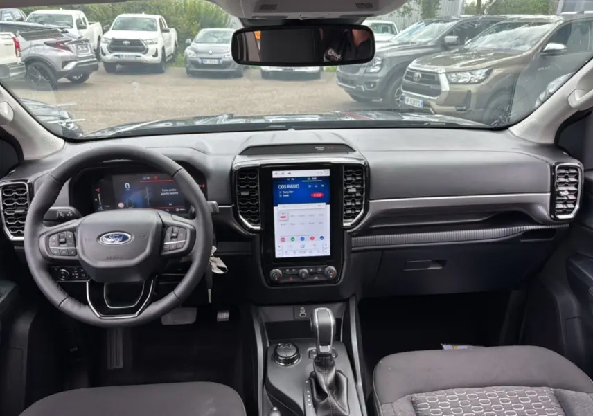 Vue intérieure du Ford Ranger 2025 gris carbone, avec tableau de bord moderne et écran tactile vertical central.
