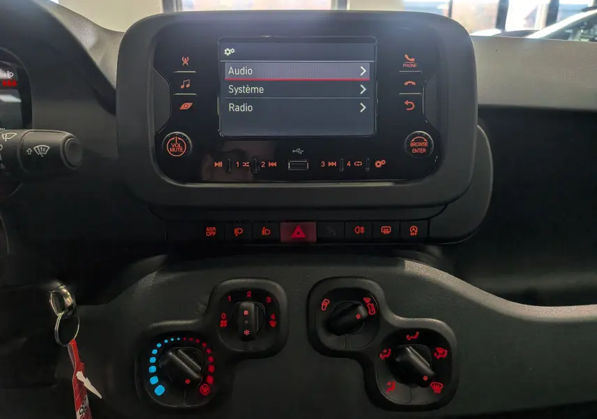 Vue rapprochée du tableau de bord noir de la Fiat Panda 2025 avec écran tactile et commandes climatiques manuelles.