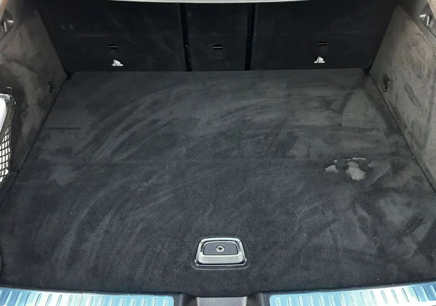 Coffre ouvert vu de l'arrière d'un Mercedes GLC Coupé blanc, tapis de coffre noir avec cache de rangement intégré.