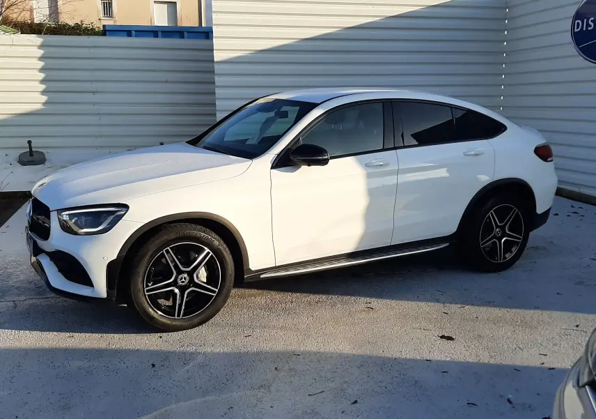 Mercedes GLC Coupé 300 4MATIC blanc vu de côté gauche, jantes AMG noires et toit incliné caractéristique.