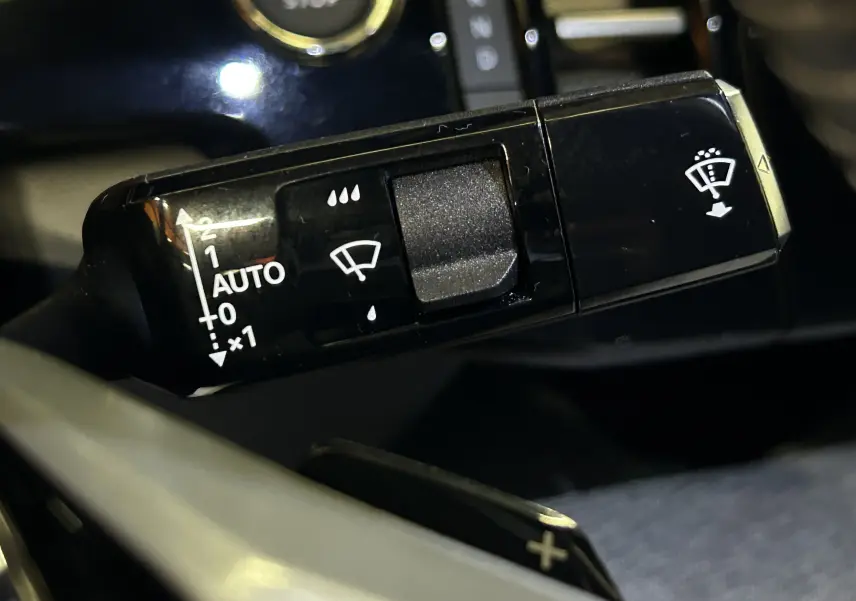 Gros plan sur la commande noire des essuie-glaces du Peugeot 3008 III Hybrid 145, avec réglages visibles en blanc.