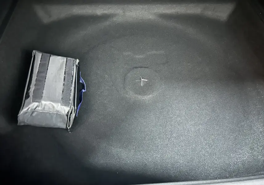 Détail du coffre noir du Peugeot 3008 III Hybrid 145 e-DSC6 Allure avec une trousse de secours grise posée.