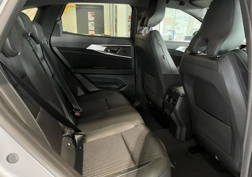 Vue intérieure côté gauche des sièges arrière gris avec sellerie mixte tissu carbone Alcantara et surpiqûres bleues du Renault Austral 2025.