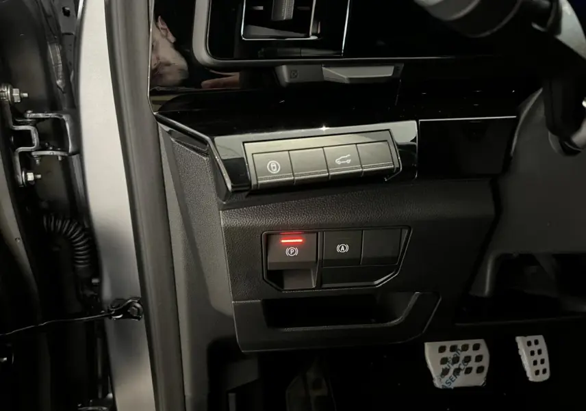 Vue intérieure côté gauche du tableau de bord du Renault Austral gris, avec commandes de frein à main et hayon motorisé.