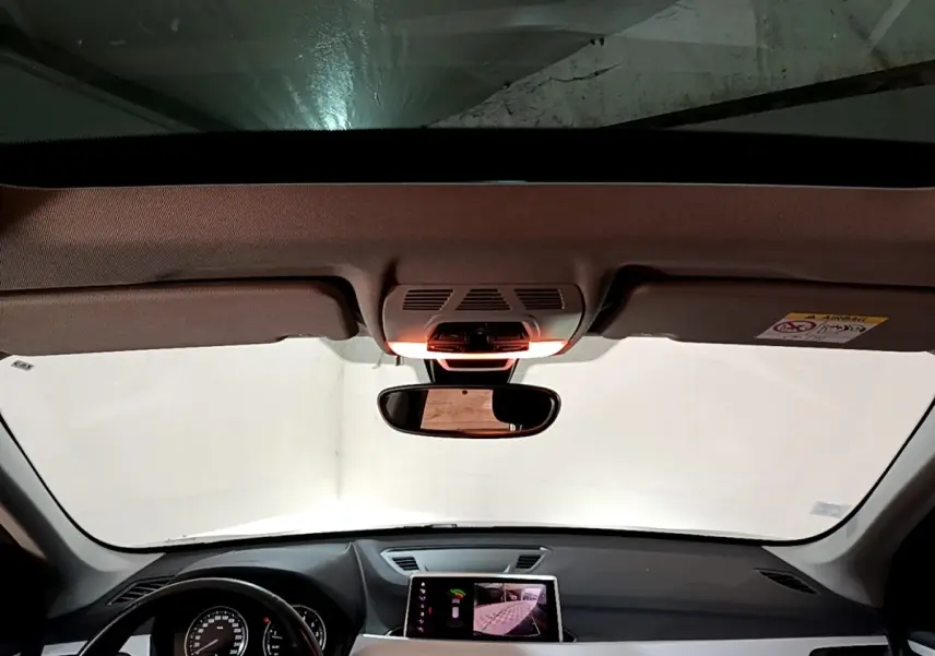 Vue intérieure du tableau de bord et volant noir d'une BMW X1 2020 avec écran tactile central allumé.