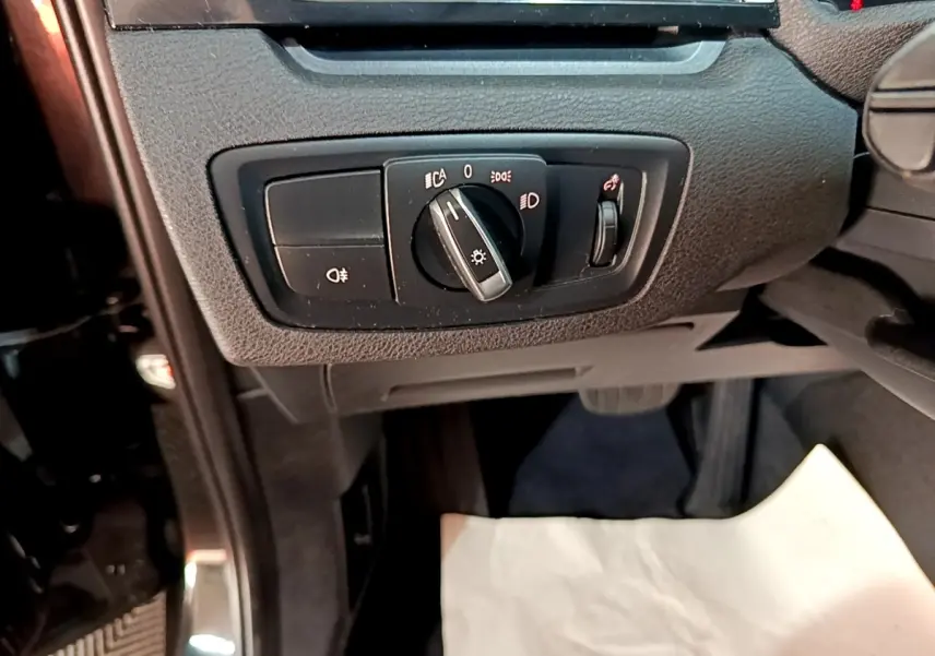 Gros plan sur le panneau de commande des phares noir dans l'habitacle d'une BMW X1 sDrive20i 2020.