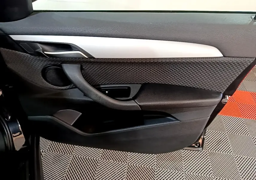 Vue intérieure du panneau de porte arrière gauche noir de la BMW X1 sDrive20i Business Design 2020 avec insert tissu et poignée intégrée.