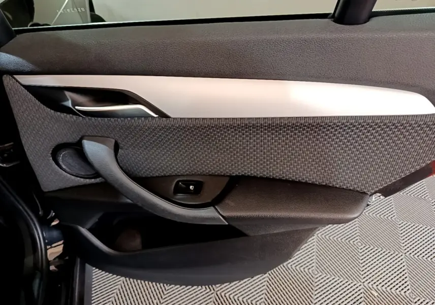 Vue intérieure côté gauche de la porte arrière noire du BMW X1 2020 avec garniture tissu et poignée intégrée.