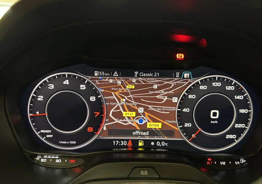 Tableau de bord numérique Audi Q2 TFSI 110 gris, affichage GPS central et compte-tours à gauche en vue frontale.