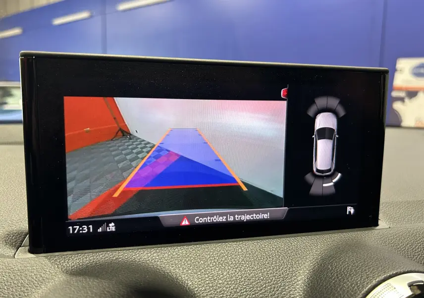 Écran de caméra de recul et capteurs de stationnement d’un Audi Q2 gris, vue intérieure du tableau de bord.