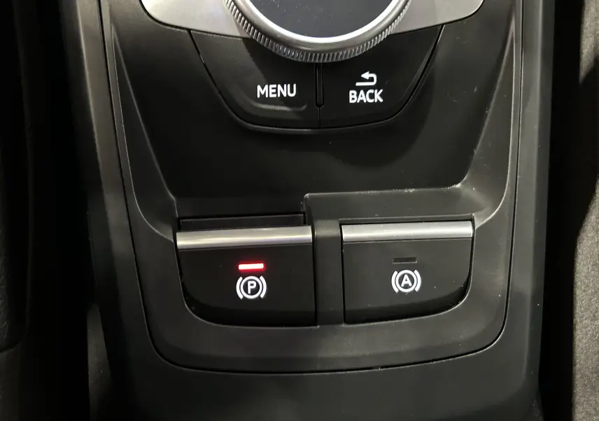 Gros plan sur la console centrale noire de l'Audi Q2 avec boutons de frein à main électronique et arrêt auto.