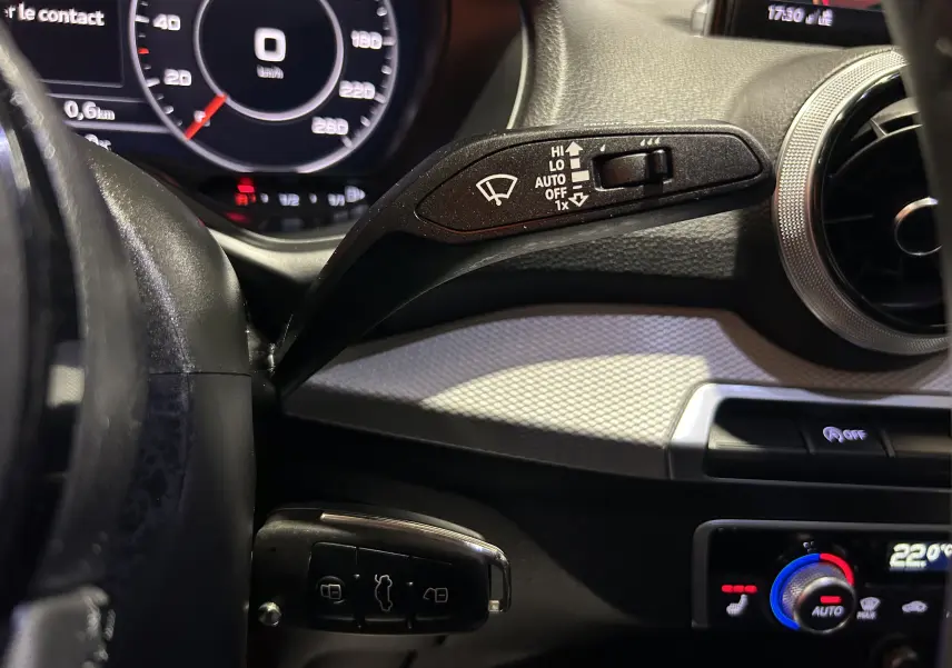 Détail intérieur côté gauche du tableau de bord gris d’Audi Q2 2023 avec commandes essuie-glace et climatisation digitale.