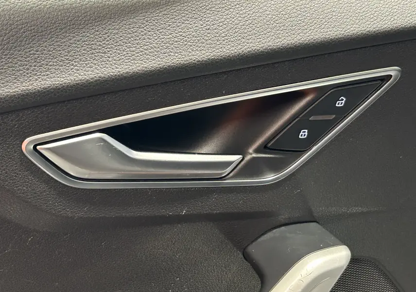 Gros plan sur la poignée intérieure côté gauche d'une Audi Q2 2023 gris avec commandes de verrouillage intégrées.