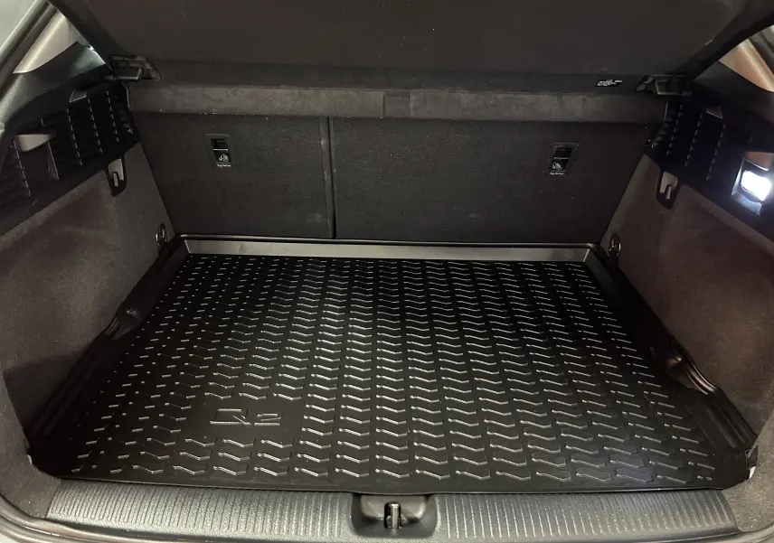 Coffre ouvert de l'Audi Q2 gris, vue intérieure montrant le tapis de coffre noir avec logo Q2 et éclairage latéral.