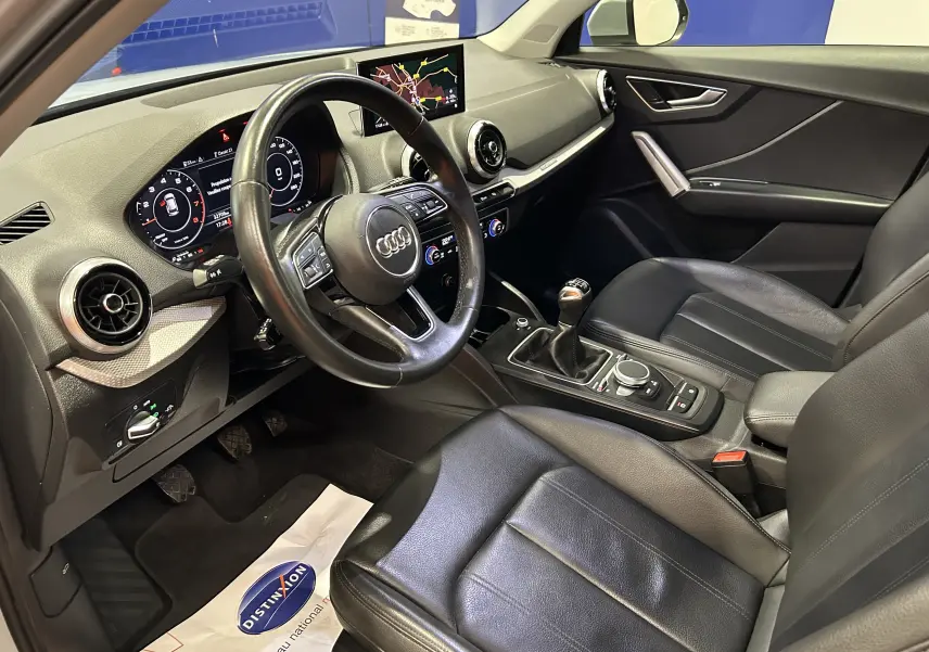 Intérieur noir cuir de l'Audi Q2 TFSI 110, vue côté conducteur avec tableau de bord digital et GPS affiché.