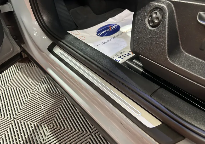 Gros plan sur la marche d'entrée côté conducteur d'un Audi Q2 gris, avec seuil en aluminium et intérieur noir.