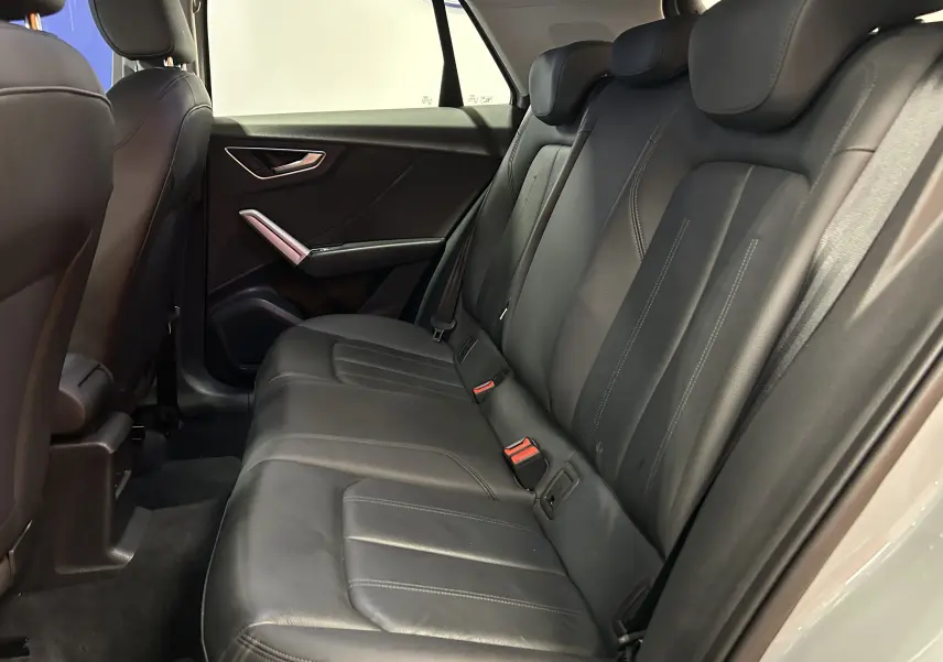 Vue intérieure côté droit des sièges arrière en cuir noir de l'Audi Q2 gris, mettant en valeur l'espace et la finition soignée.