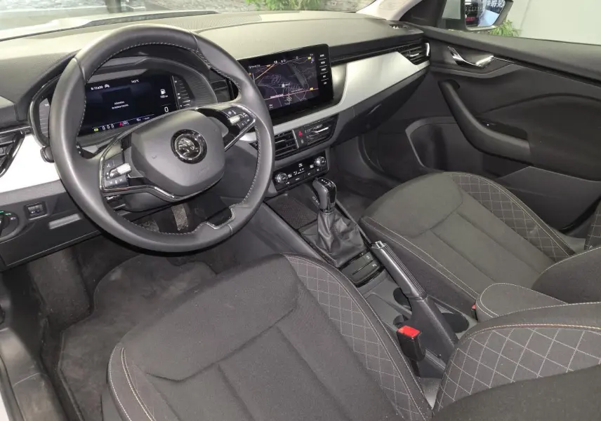 Vue intérieure côté conducteur du Skoda Kamiq 2023, avec volant cuir, écran tactile et sellerie tissu noire.